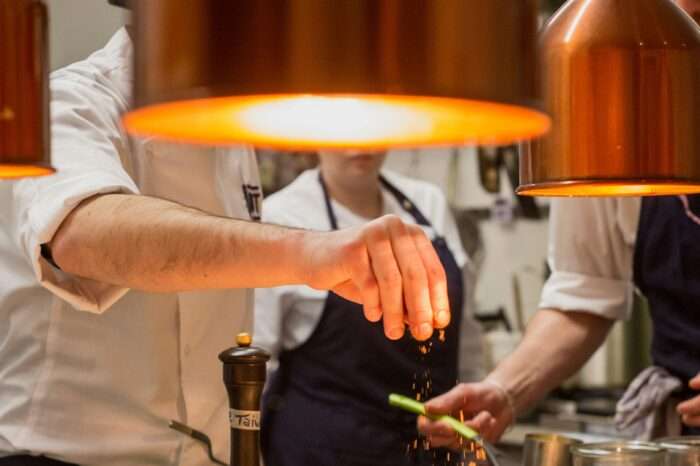 Koch würzt Speisen in einer Restaurantküche.