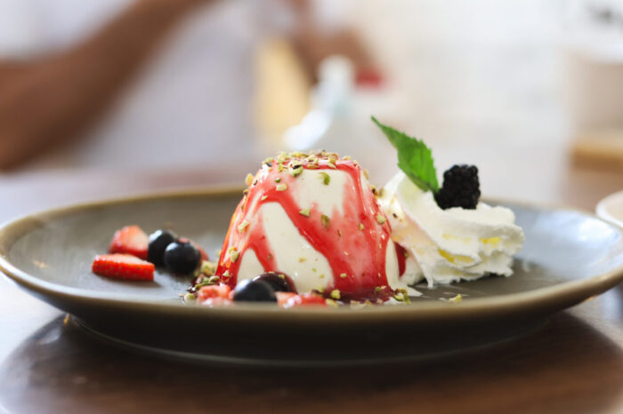 Panna cotta mit Früchten und Sahne auf Teller.