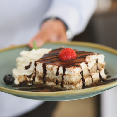 Tiramisu mit Schokoladensoße und Erdbeere auf Teller