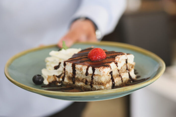 Tiramisu mit Schokoladensoße und Erdbeere auf Teller