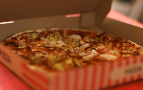 Pizza in offener Schachtel mit Artischocken.