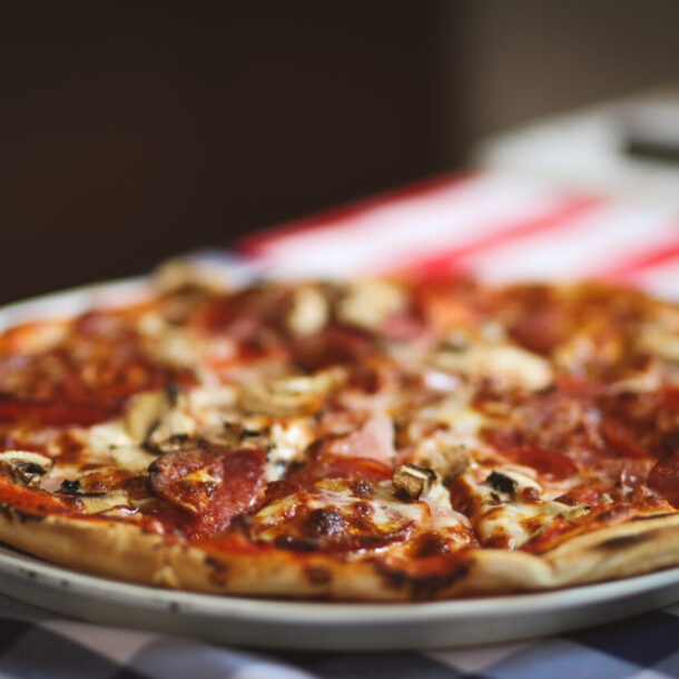 Frische Pizza auf Teller mit Salami und Pilzen.